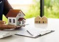 A real estate agent offers a sample home insurance home to sign the agreement. with documents of the contract of sale or lease